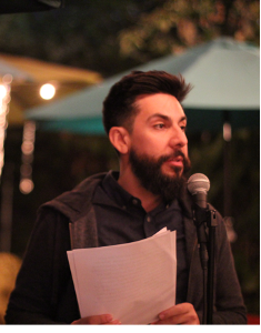 Ryan rivas standing at a microphone with paper in hand